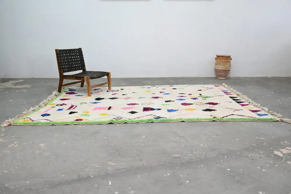 A vibrant cream-colored DecorBites™ handmade Moroccan azilal rug with geometric patterns and bold green border