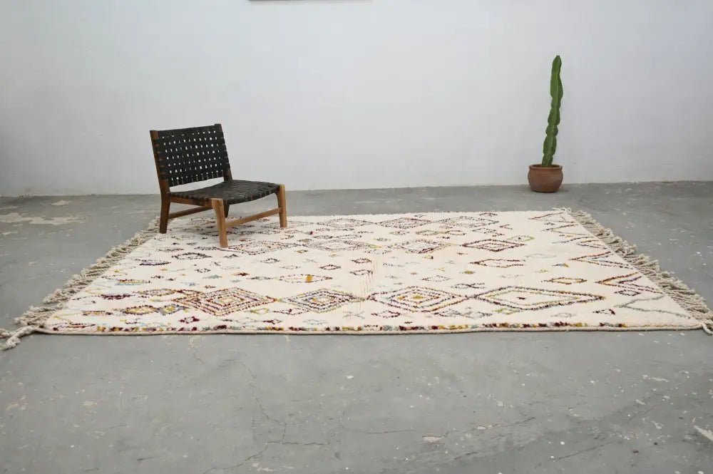 Cream-colored handmade moroccan azilal rug with intricate geometric patterns in earthy tones and fringed edges 305x206cm