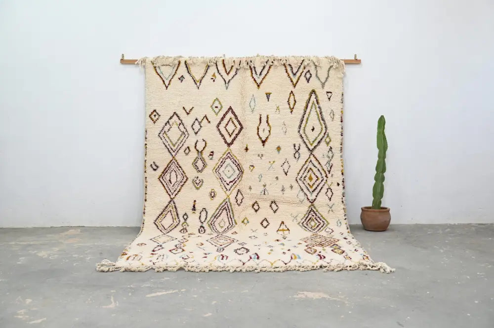 Cream-colored decorbites™ handmade moroccan azilal rug 305x206cm with intricate geometric patterns and fringed edges