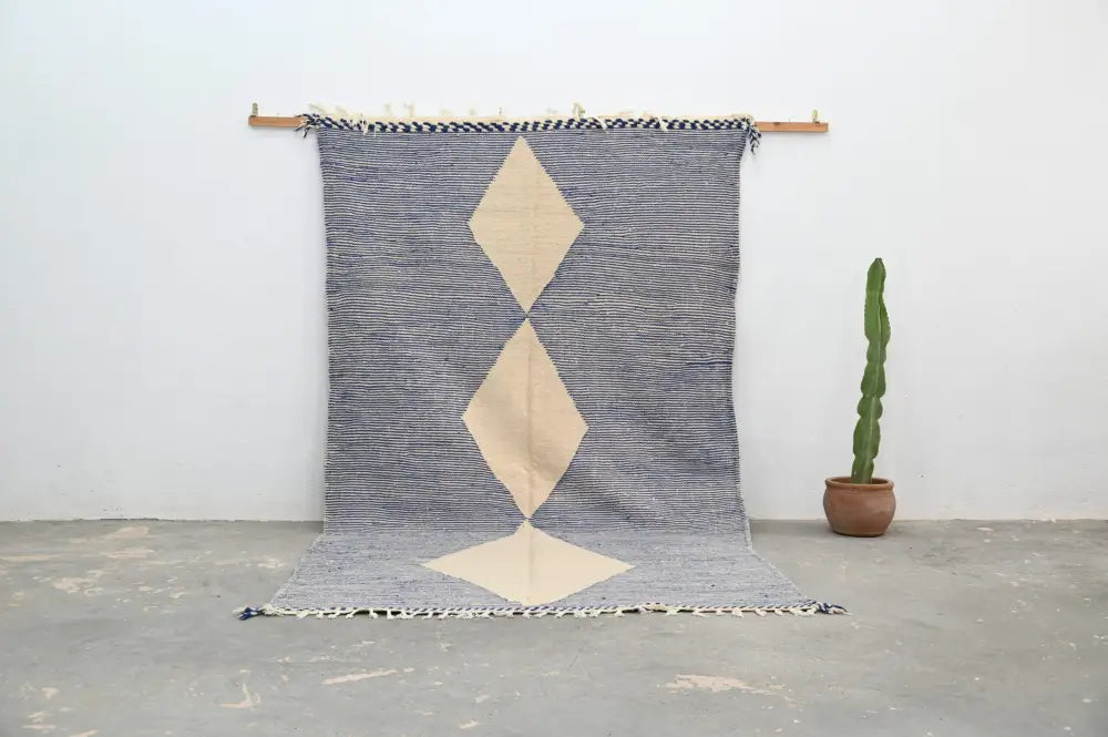Gray and cream geometric decorbites handmade moroccan azilal rug 306x177cm with bold diamond pattern hanging on wooden rod