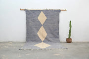 Gray and cream geometric decorbites handmade moroccan azilal rug 306x177cm with bold diamond pattern hanging on wooden rod