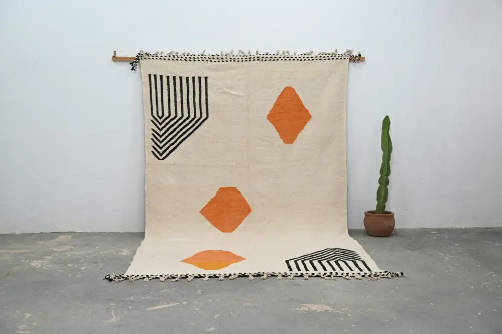 Beige woven handmade moroccan azilal rug with bold black and orange geometric patterns and fringed edges 308x200 cm