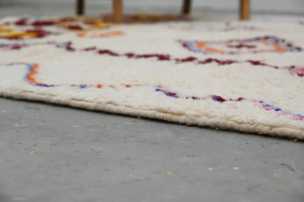 Cream-colored handmade moroccan azilal rug with intricate burgundy orange and blue woven patterns 309x207cm