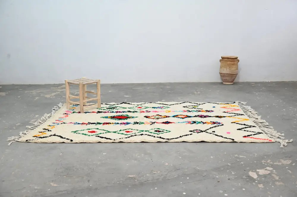 Cream-colored decorbites™ handmade traditional azilal rug with intricate geometric patterns and fringed edges 240x150cm