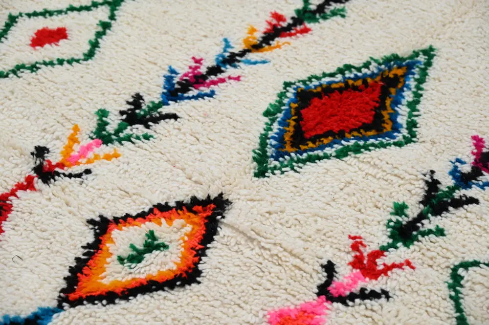 Cream-colored DecorBites™ handmade traditional azilal rug with vibrant red green blue orange and black geometric patterns