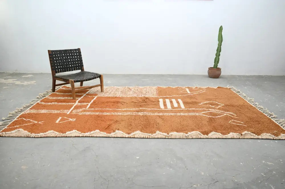A terracotta handmade traditional azilal rug with cream geometric patterns and fringed edges measuring 328x197cm