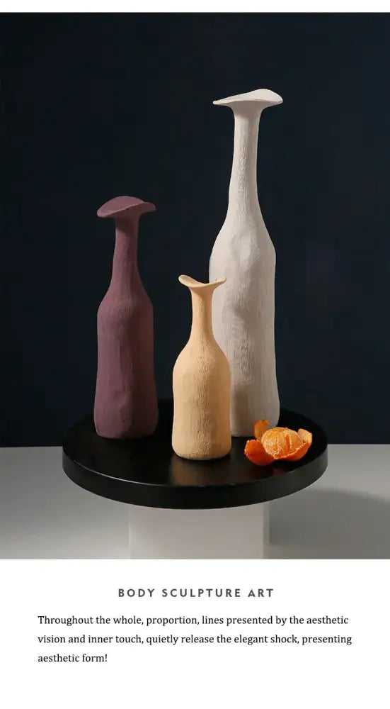 Three slender handmade nordic ceramic flower vases in muted purple beige and off-white on a black tray