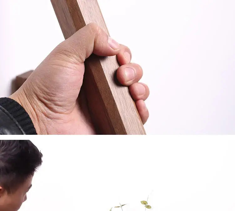 A hand gripping a sleek dark brown solid wood handle of the handmade nordic decorbites wall vase for plants