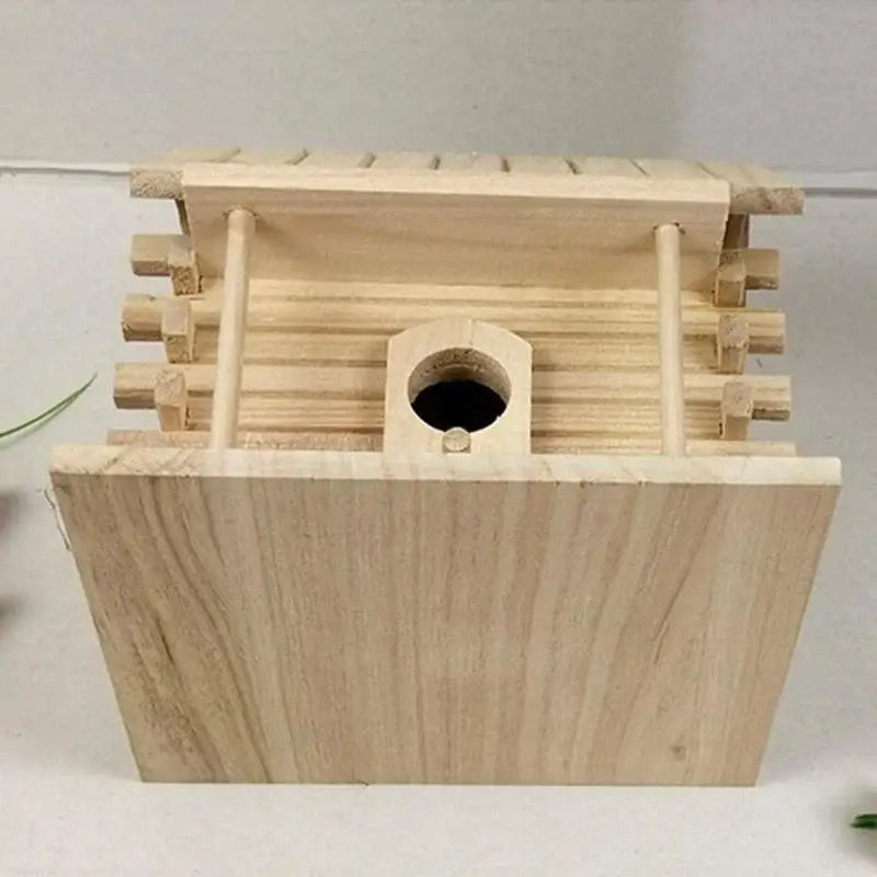 Light-colored handmade wooden DecorBites™ nest box with slatted roof and circular entrance hole for outdoor bird nest