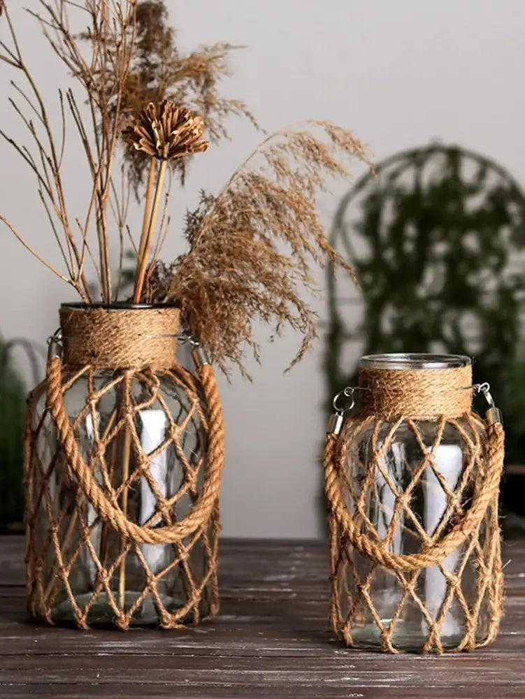 Two clear hanging glass vases with hemp rope wrapped in a rustic diamond pattern and metal ring handles by decorbites