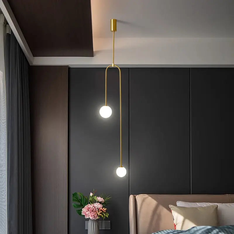 Gold-toned decorbites™ hanging lights with two spherical bulbs and a slender curved rod offering versatile lighting options