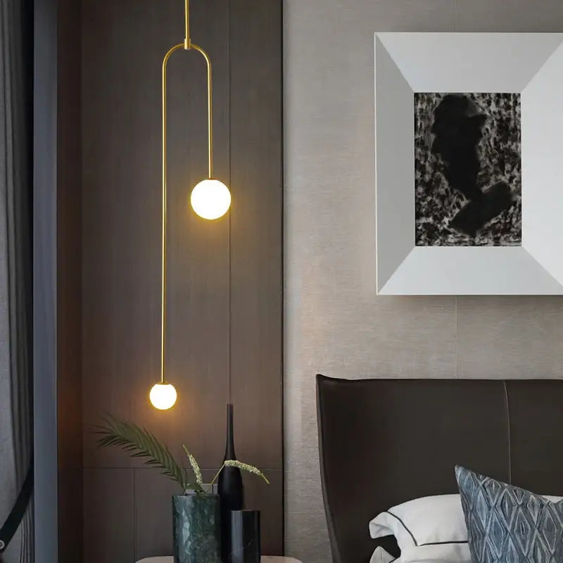 Gold-toned DecorBites™ hanging lights with two spherical glass bulbs on a curved metal arm offer versatile lighting options