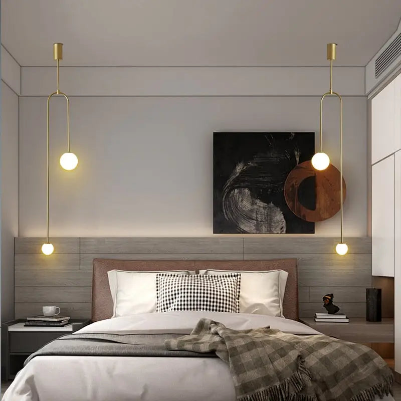 Gold-toned DecorBites™ hanging lights with spherical bulbs offer versatile lighting options in elegant gold finishes above the bed