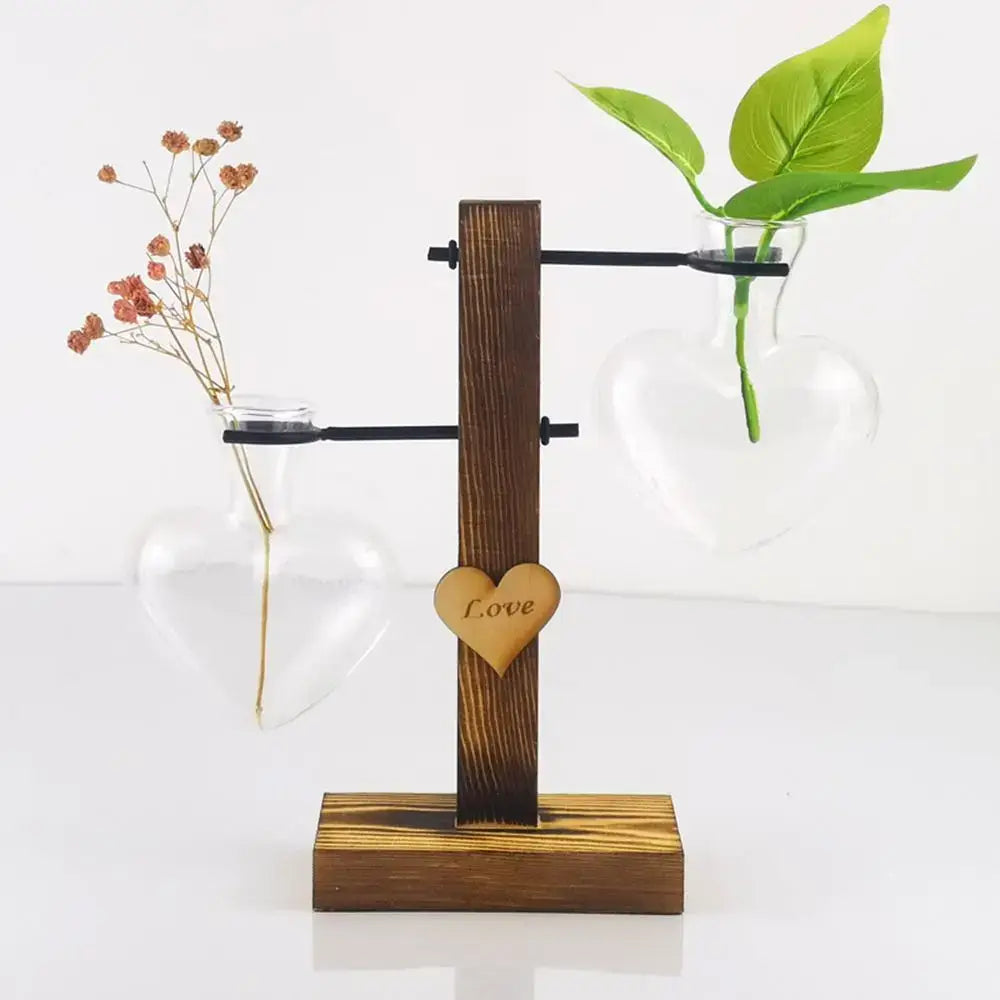 Wooden stand with two heart shape hydroponic glass vases holding dried flowers and a green plant for home decor