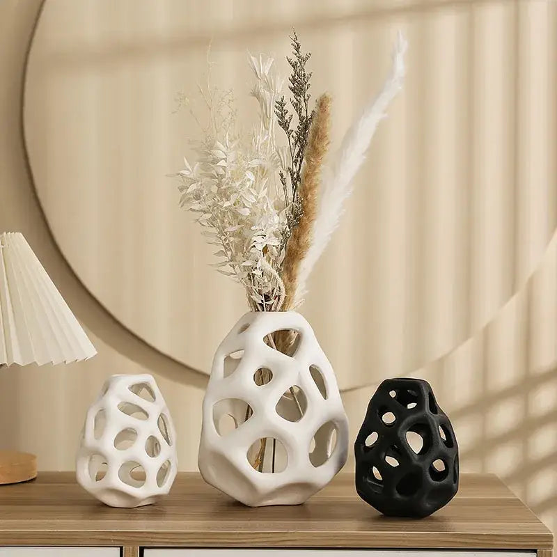 White ceramic vase with geometric perforated design and dried botanicals featuring nordic classical design