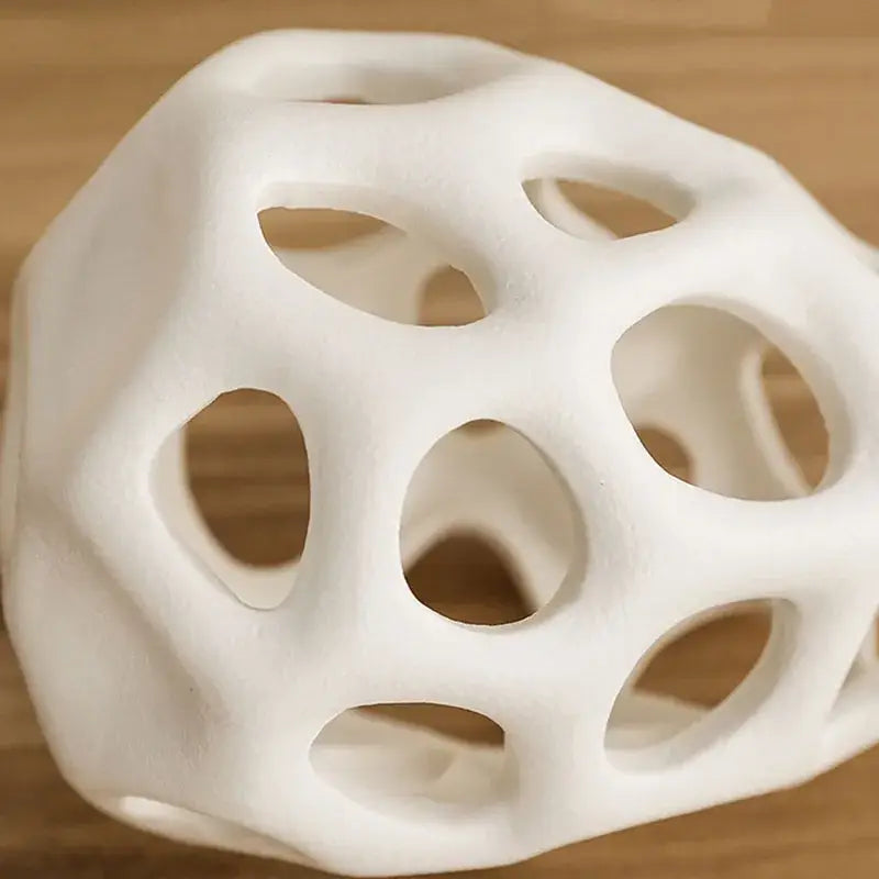 White porous ceramic vase with geometric orb shape and interconnected circular openings in nordic classical design