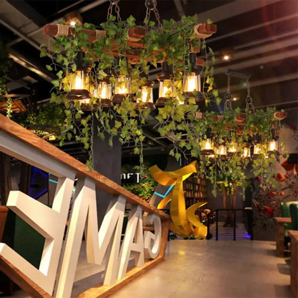 Rustic industrial black metal lantern island light with eight warm-toned lanterns and hanging green vines by decorbites