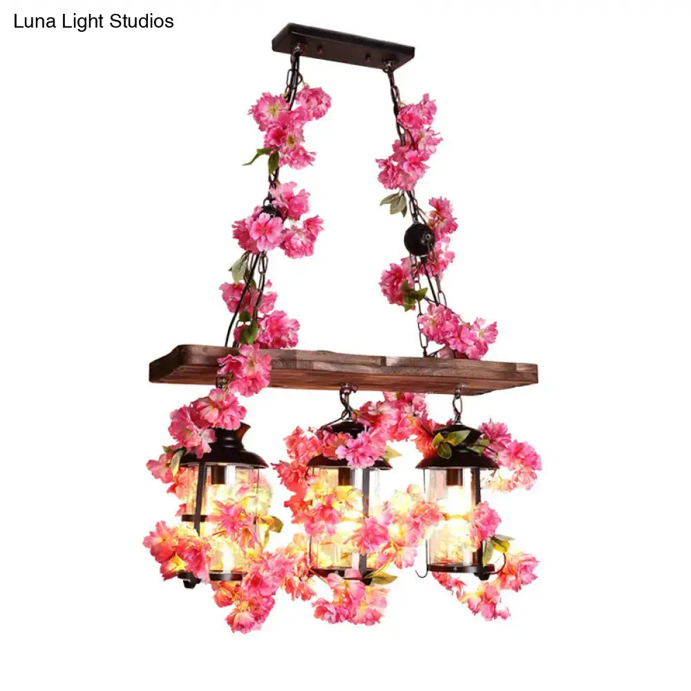 A decorbites industrial clear glass restaurant island light with three black cylindrical heads and pink floral decor