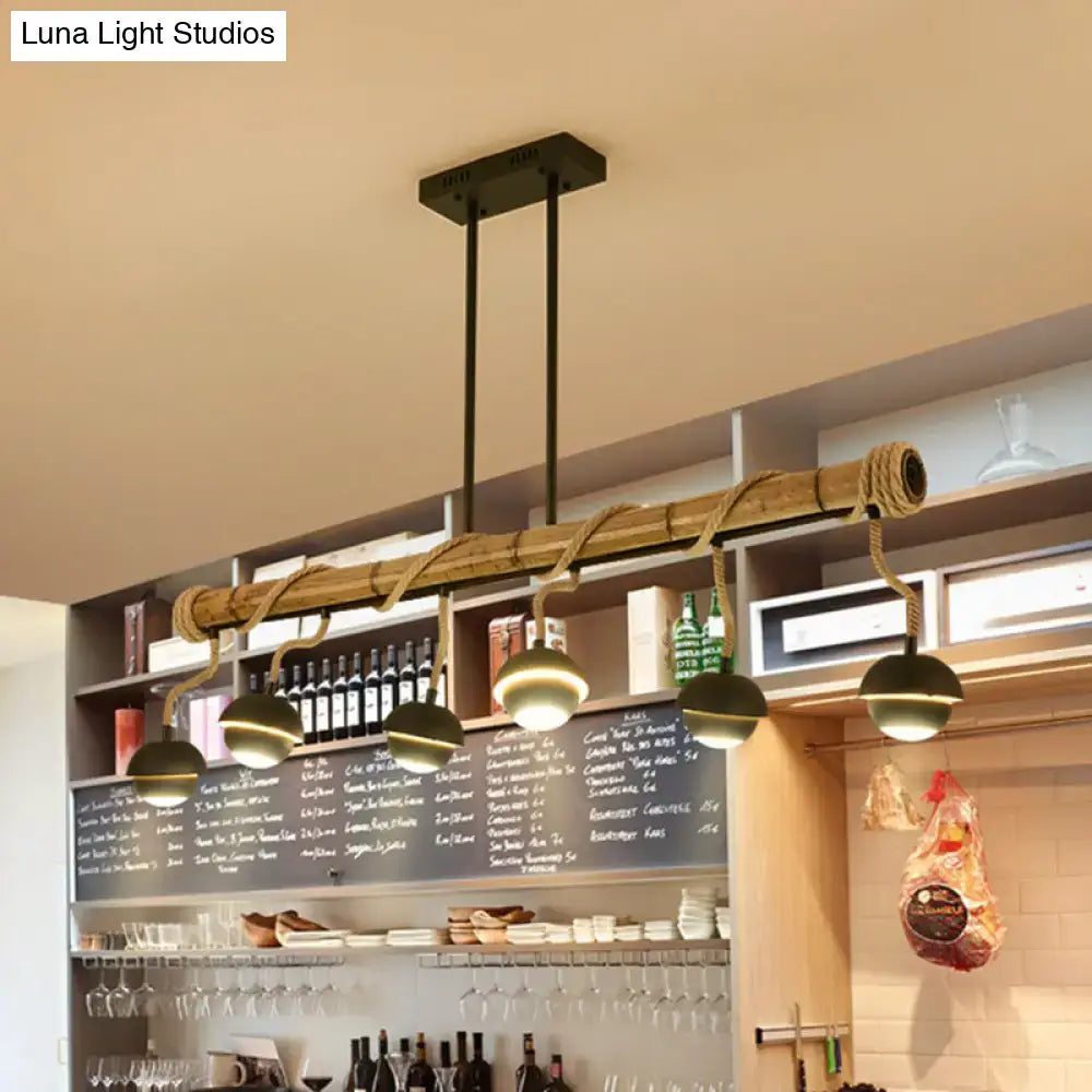 Industrial linear chandelier with rustic bamboo pole, thick rope suspension, dark green dome bulbs, and black iron finish