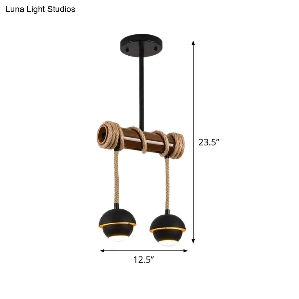 Industrial linear chandelier with two black iron pendant bulbs accented by gold rims suspended on rustic bamboo beam