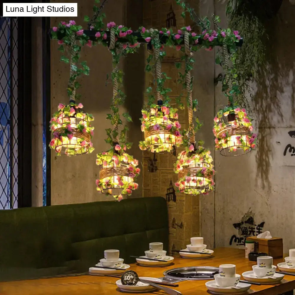Five black cage island pendant lights with woven metal cages and pink green artificial flowers for cage island lighting