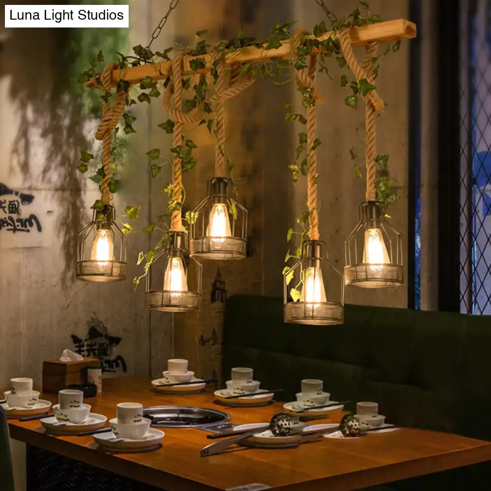Rustic wooden beam with hanging rope and green ivy supports four warm glowing bulbs in decorbites industrial metal caged island pendant light brown