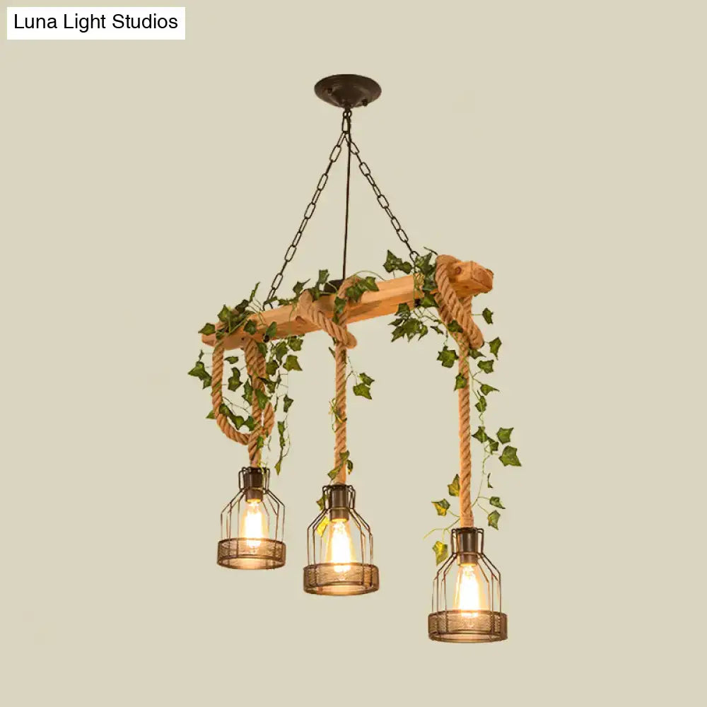 Decorbites industrial metal caged island pendant light with three brown glass lanterns hanging by rope and green ivy
