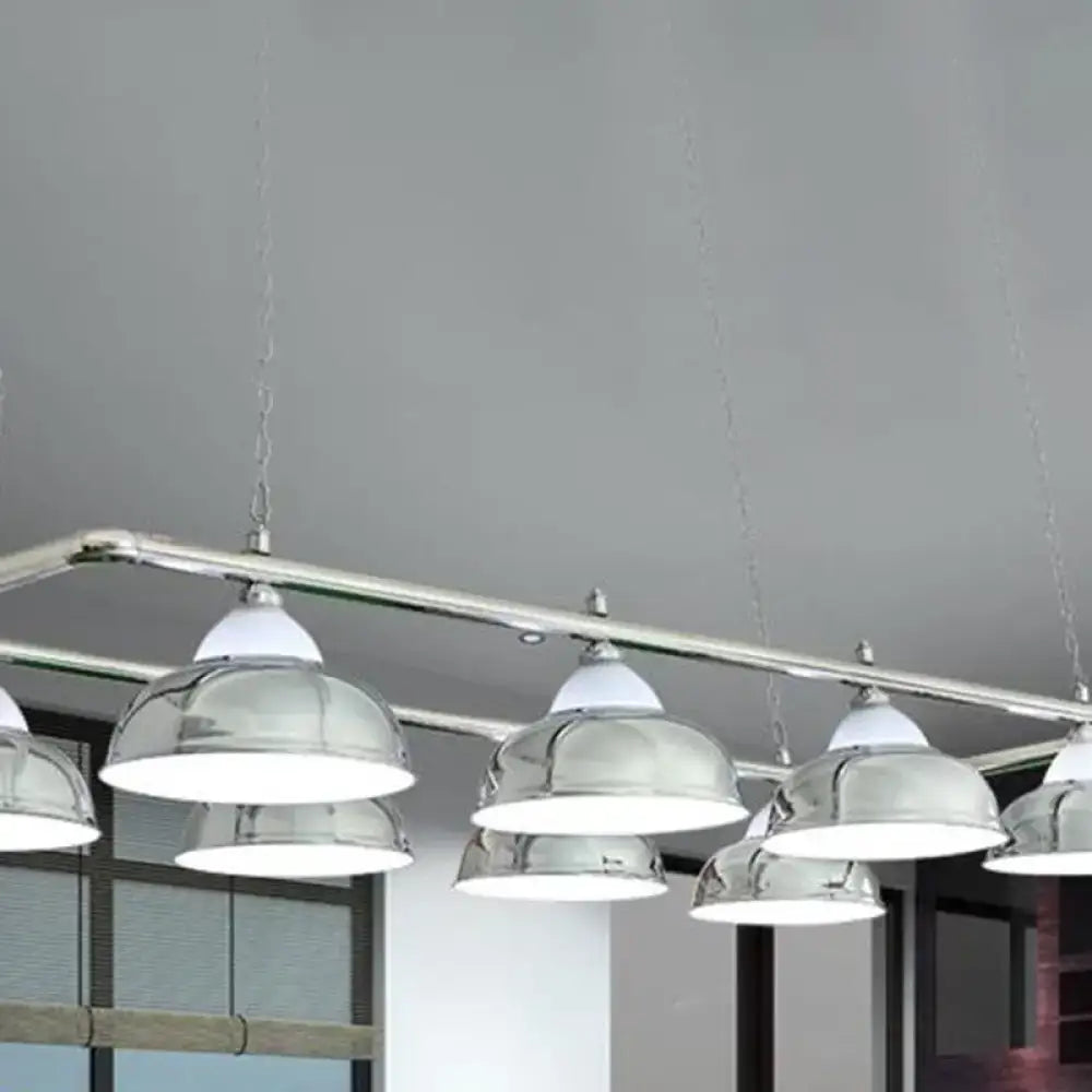 Chrome-finished dome-shaped metal mirrored bowl pendant lights with white shades suspended from a sleek metal bar