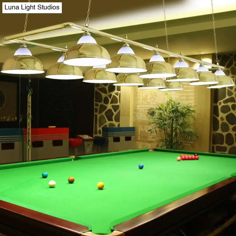 Gold-colored industrial metal mirrored bowl pendant lights suspended in a row above a green pool table