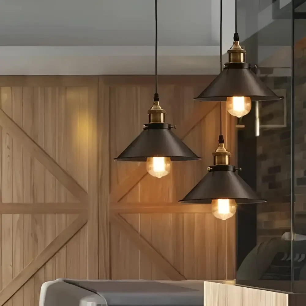 Three black industrial pendant lights with brass accents and warm exposed bulbs in decorbites™ pendant lighting