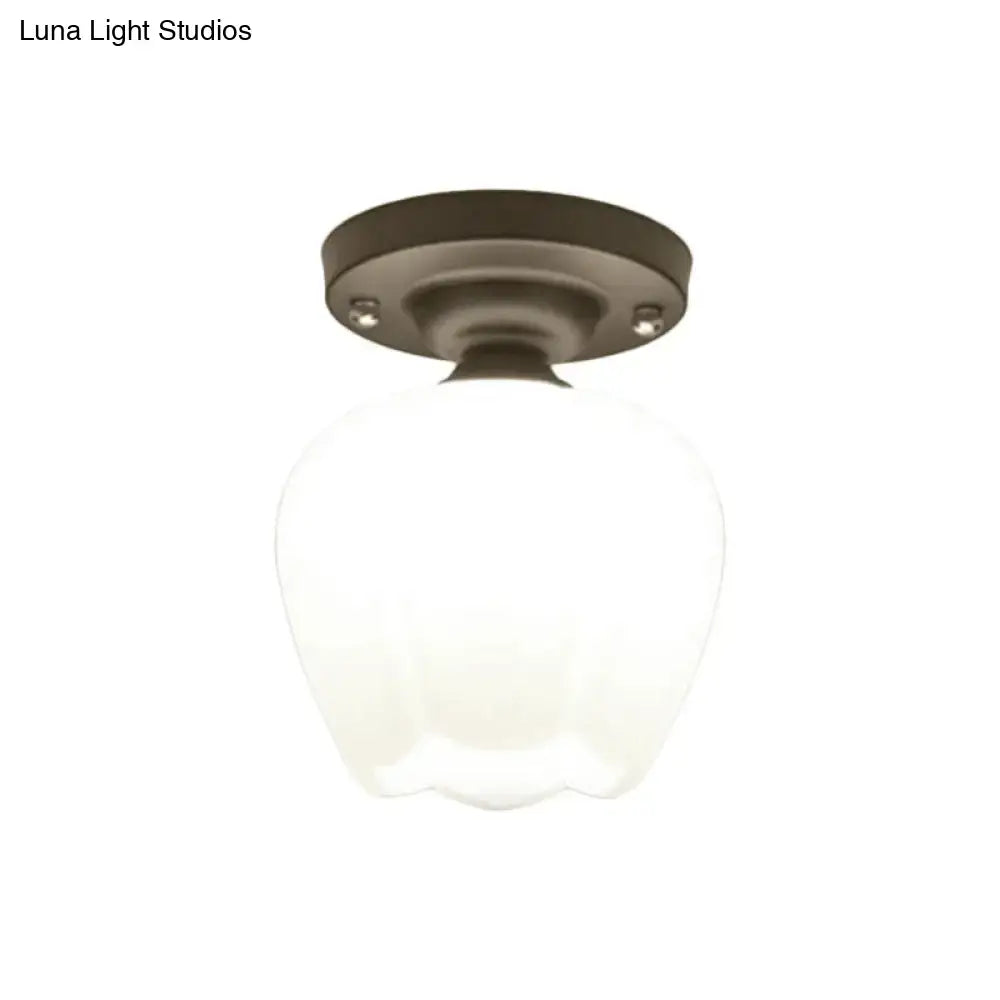 A frosted black opal glass globe with a scalloped base on a dark bronze mount for corridor lighting fixture