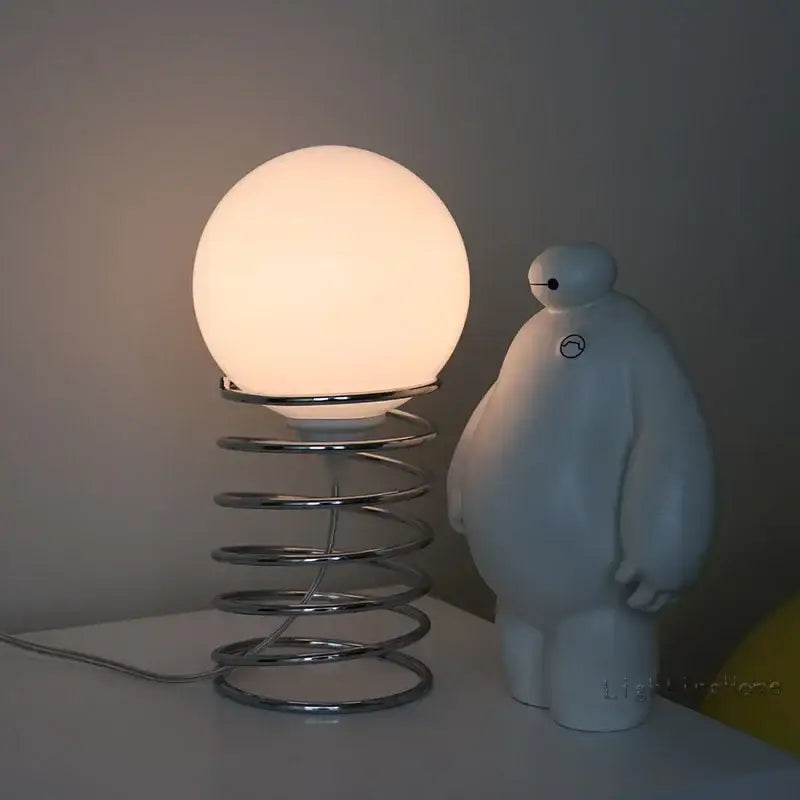 A glowing white glass ins bauhaus spring lamp with chrome spring base for living room and bedroom decor
