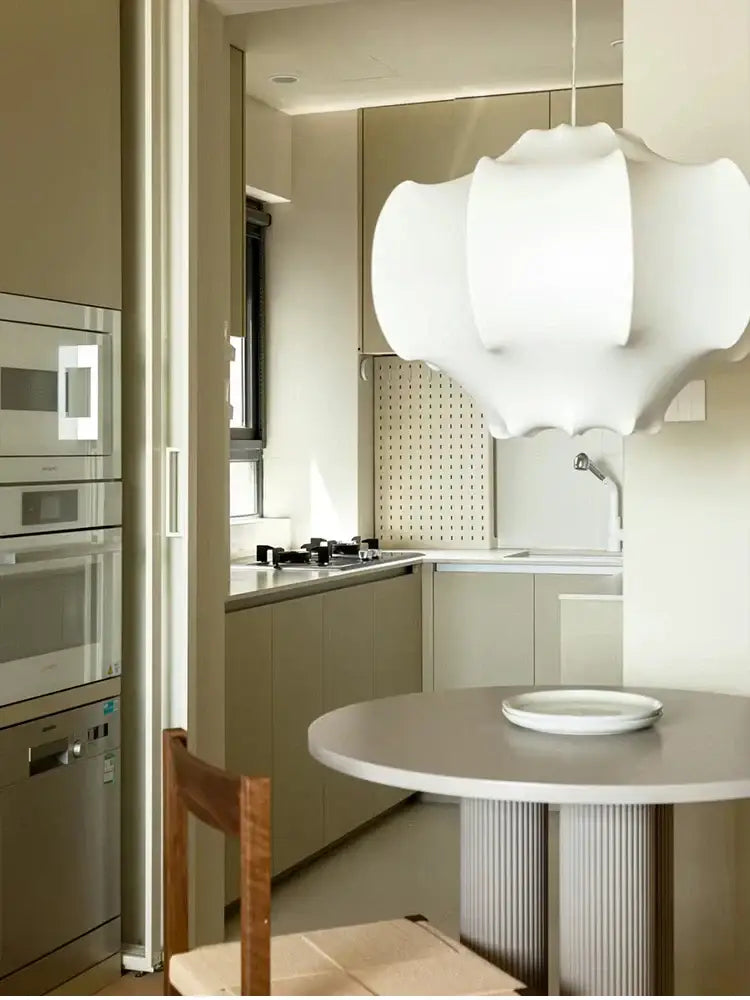 White sculptural pendant light with layered italian silk design by decorbites hanging above round dining table