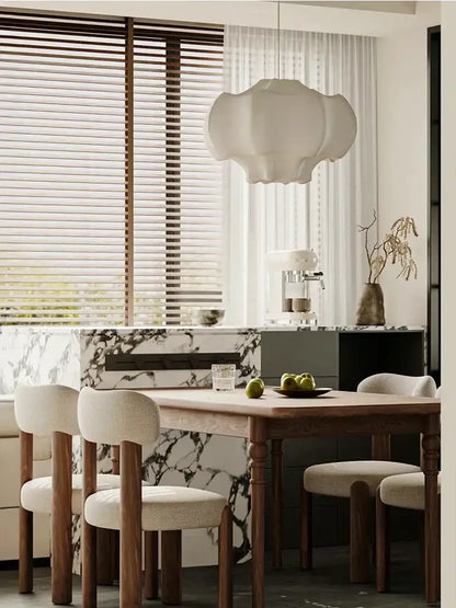 A modern cloud-shaped decorbites italian silk pendant light with soft white fabric shade hangs above dining table