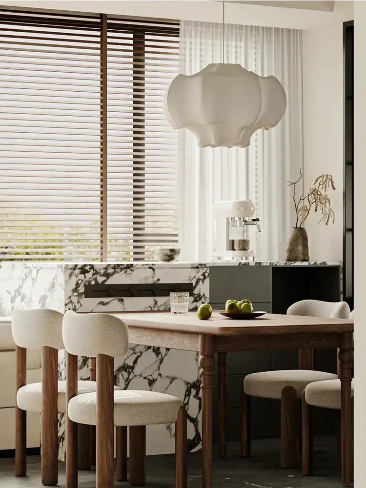 A modern cloud-shaped decorbites italian silk pendant light with soft white fabric shade hangs above dining table