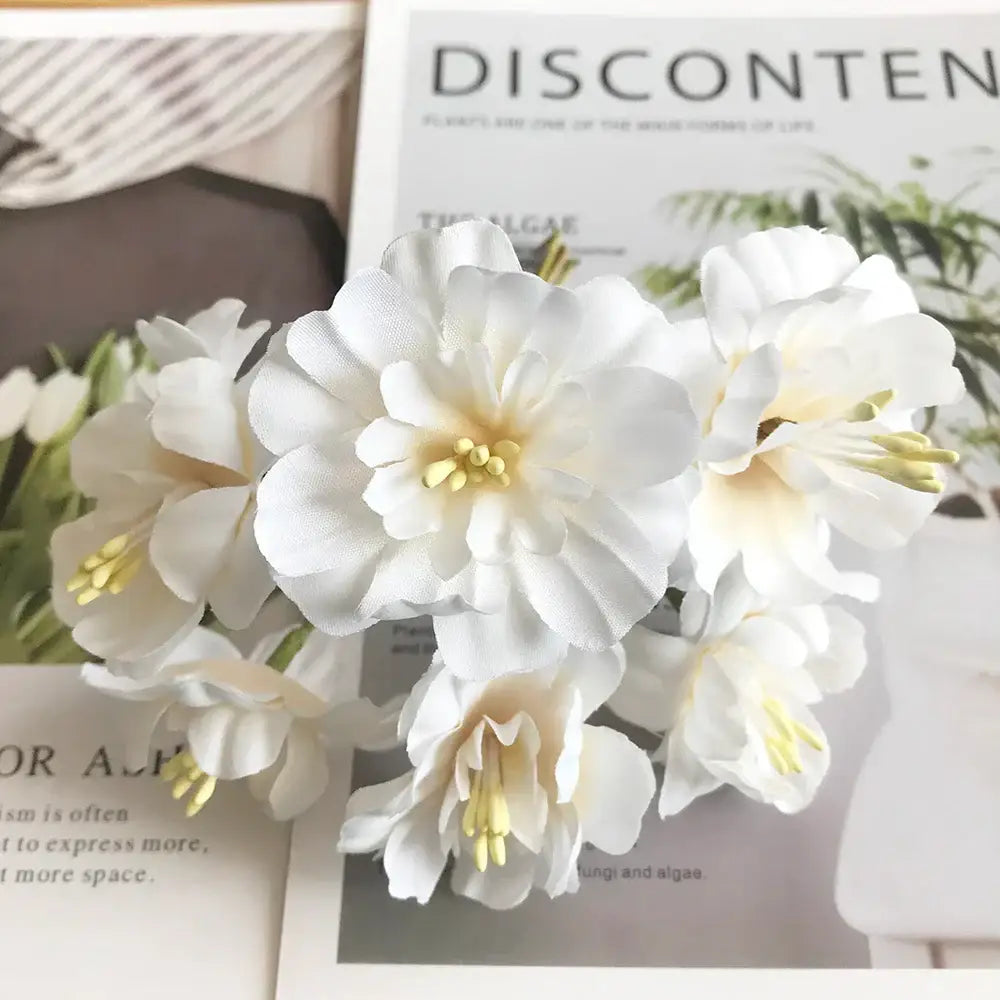 A cluster of decorbites ivory flower cherry stamen berries in white fabric with cream centers for wedding decor