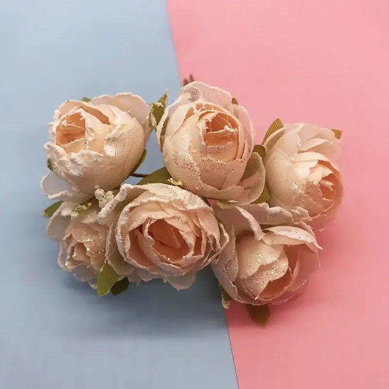 A cluster of blush pink fabric roses with glitter accents and green stems in decorbites ivory flower cherry wedding decor