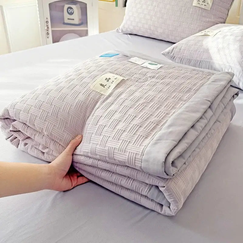 A soft light gray decorbites jacquard summer cool blanket with subtle woven texture and neatly folded edges