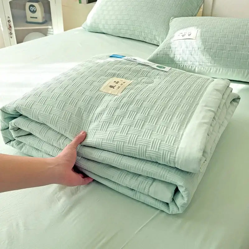 A neatly folded mint green decorbites jacquard summer cool blanket with textured woven pattern and plush fabric