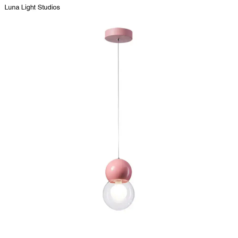 Pink kids bedside pendulum light featuring a spherical pendant with a clear glass globe and macaron ceiling pendant design