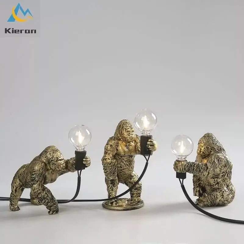 Three golden decorbites king kong led desk lamps in black resin holding lit bulbs for living room lighting