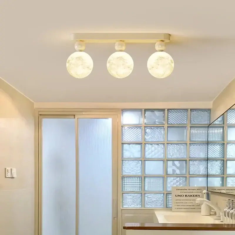Modern decorbites led ceiling fixture with three frosted glass globes and matte cream metal bar for bedroom lighting