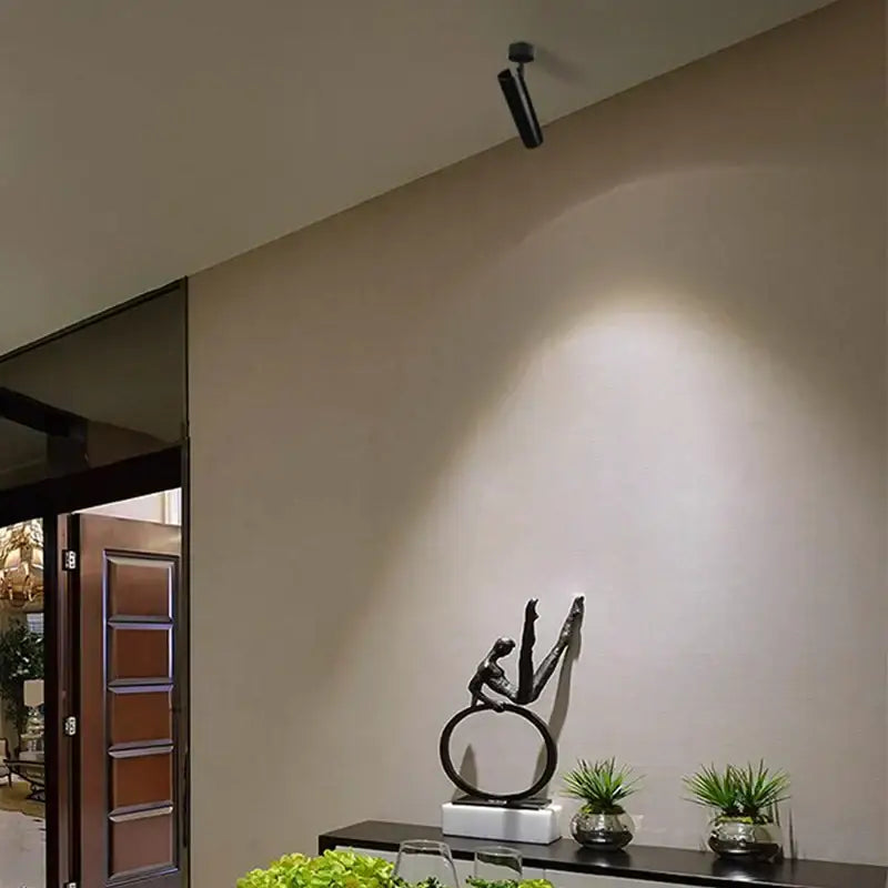 Black metallic sculpture figure in mid-air on white base shown with DecorBites led ceiling 7W 360+90 rotation spotlight