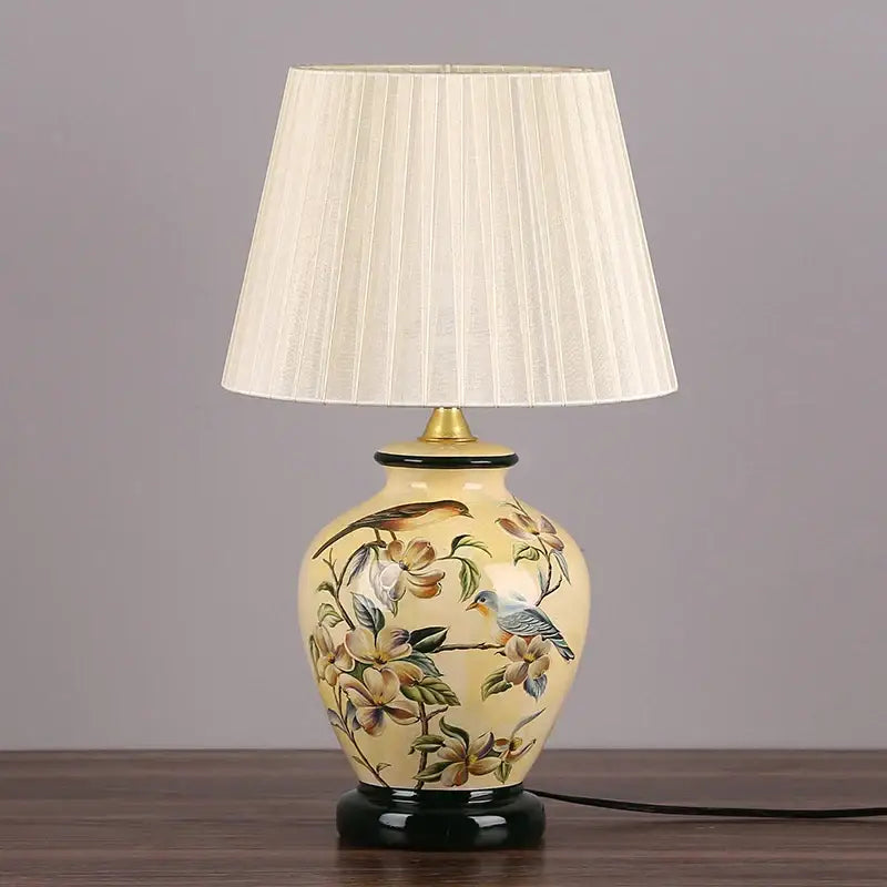 Cream-colored decorbites led ceramic table lamp with hand-painted birds and blossoms and pleated fabric shade for living room