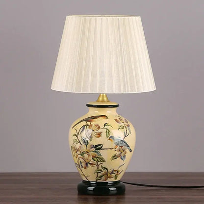 Cream-colored decorbites led ceramic table lamp with hand-painted birds and blossoms and pleated fabric shade for living room
