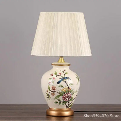 Cream-colored decorbites led ceramic table lamp with hand-painted blue bird floral design and gold-toned metal base