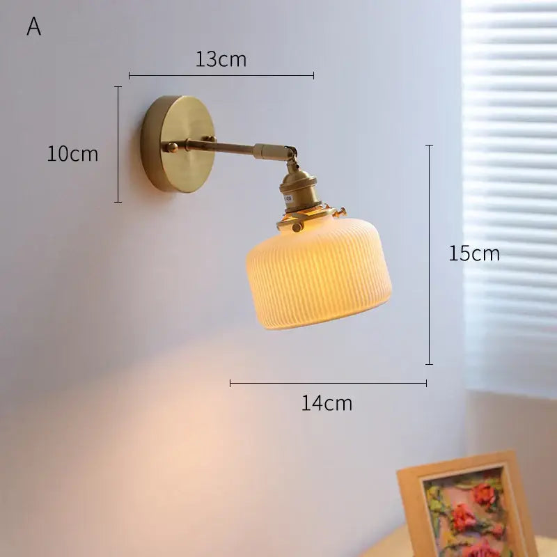 Brass-finished DecorBites LED ceramic wall sconce with ribbed warm-toned glass shade and knob switch for bedroom lighting