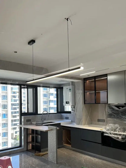 Modern minimalist kitchen with sleek black cabinets and decorbites led chandelier with white countertops and island lighting