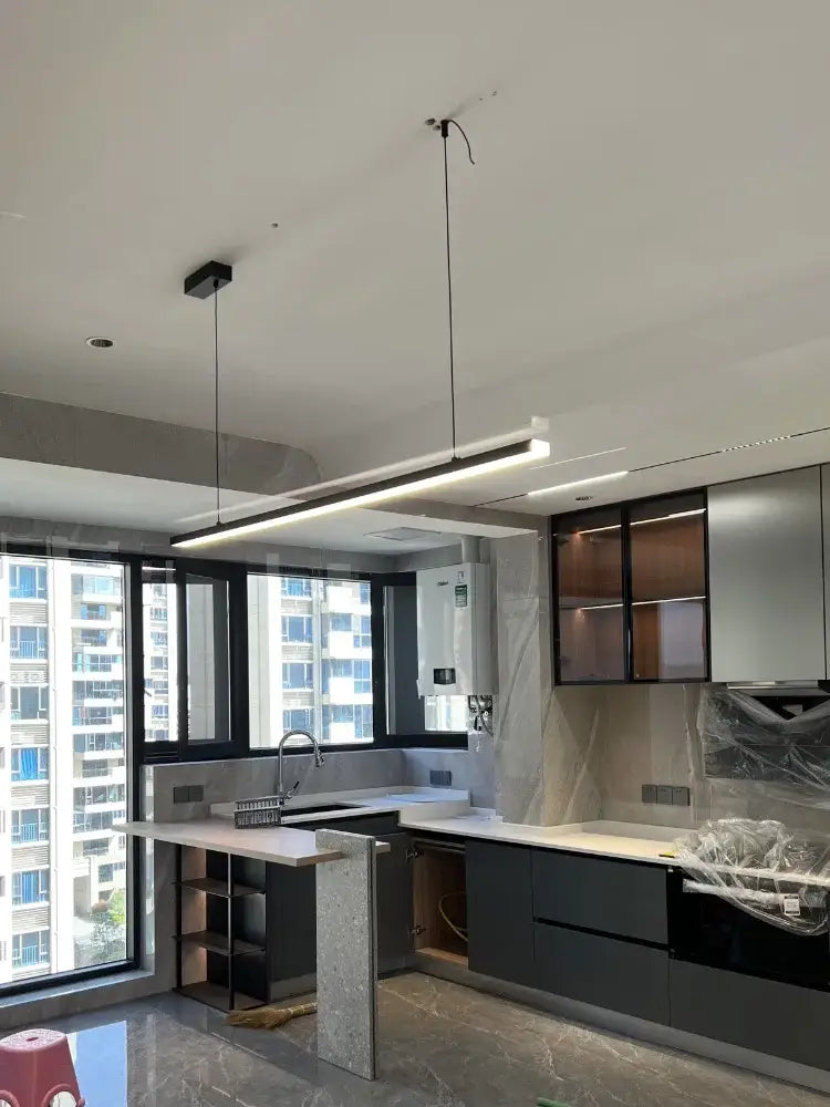 Modern minimalist kitchen with sleek black cabinets and decorbites led chandelier with white countertops and island lighting