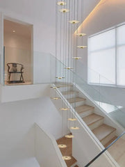 Modern minimalist decorbites led chandelier with gold-toned circular discs cascading from thin cables for staircase use
